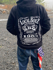 Person wearing a black hoodie with 'Local Boyz' design outdoors on a gravel surface.